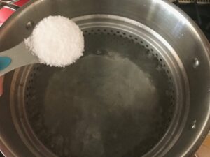adding salt to the pot of water