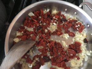 adding the tomatoes to the garlic