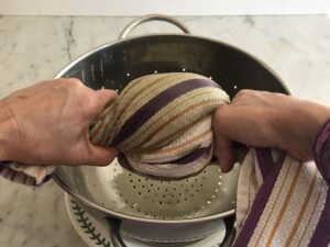 colander with greens rolled up in a dishtowel