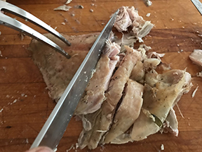A knife slicing turkey into smaller pieces.